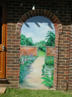 An outdoor trompe l'oeil mural of a garden arch